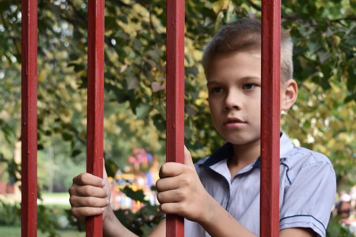 Мальчик смотрит через забор